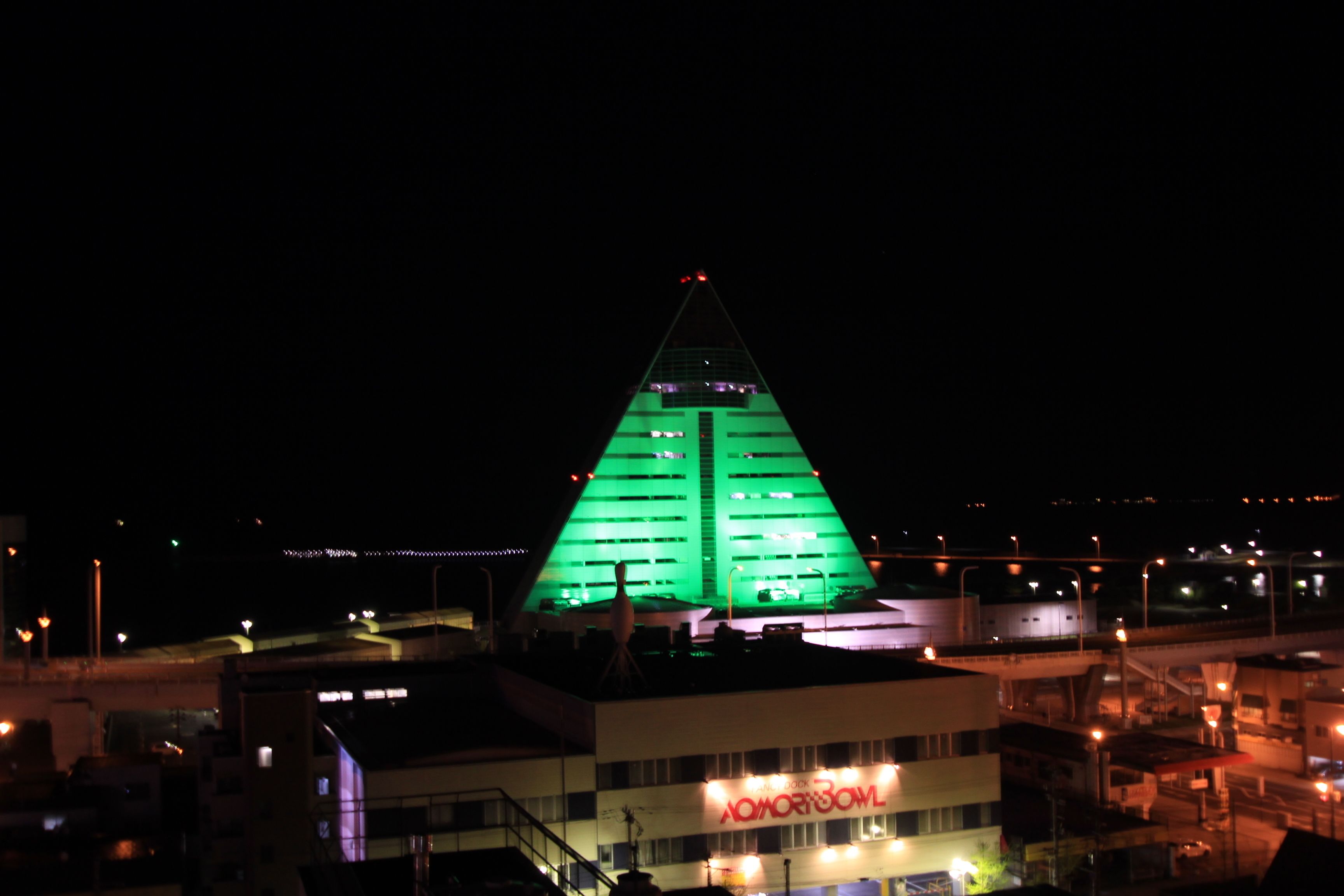 A building with a green-lit pyramid structure and a sign reading "OMOROS".