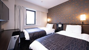 Hotelkamer met twee bedden, een televisie, een raam en een muur met een bladmotief.