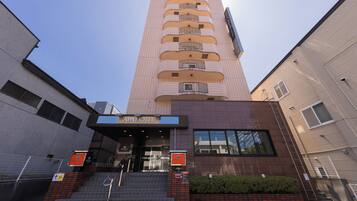 A hotel entrance with a sign reading 'APA HOTEL' and a staircase leading up to the entrance.