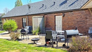Une maison en briques dotée d’un patio couvert, d’un barbecue extérieur et d’une antenne parabolique.