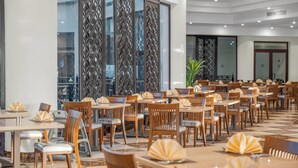 Un espaiós restaurant amb nombroses taules i cadires, grans finestres i un disseny interior modern.
