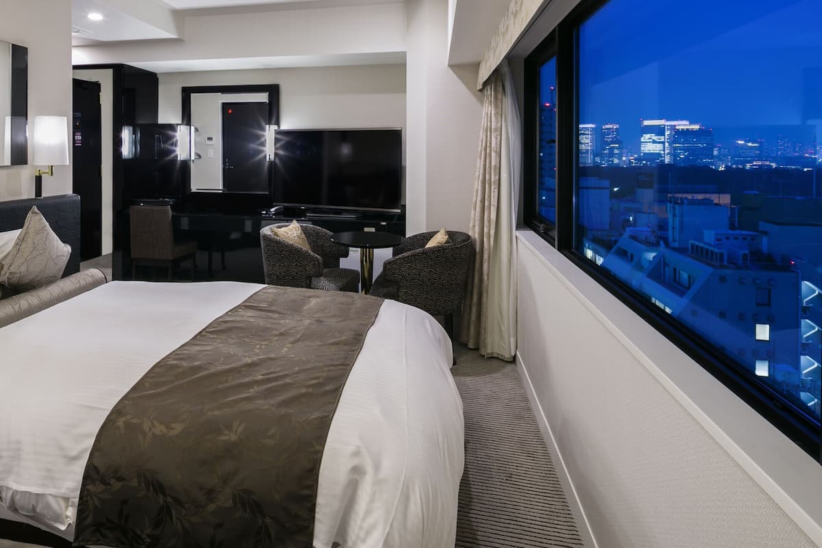 Une chambre d’hôtel avec un grand lit, un bureau, une chaise et une vue sur la ville.