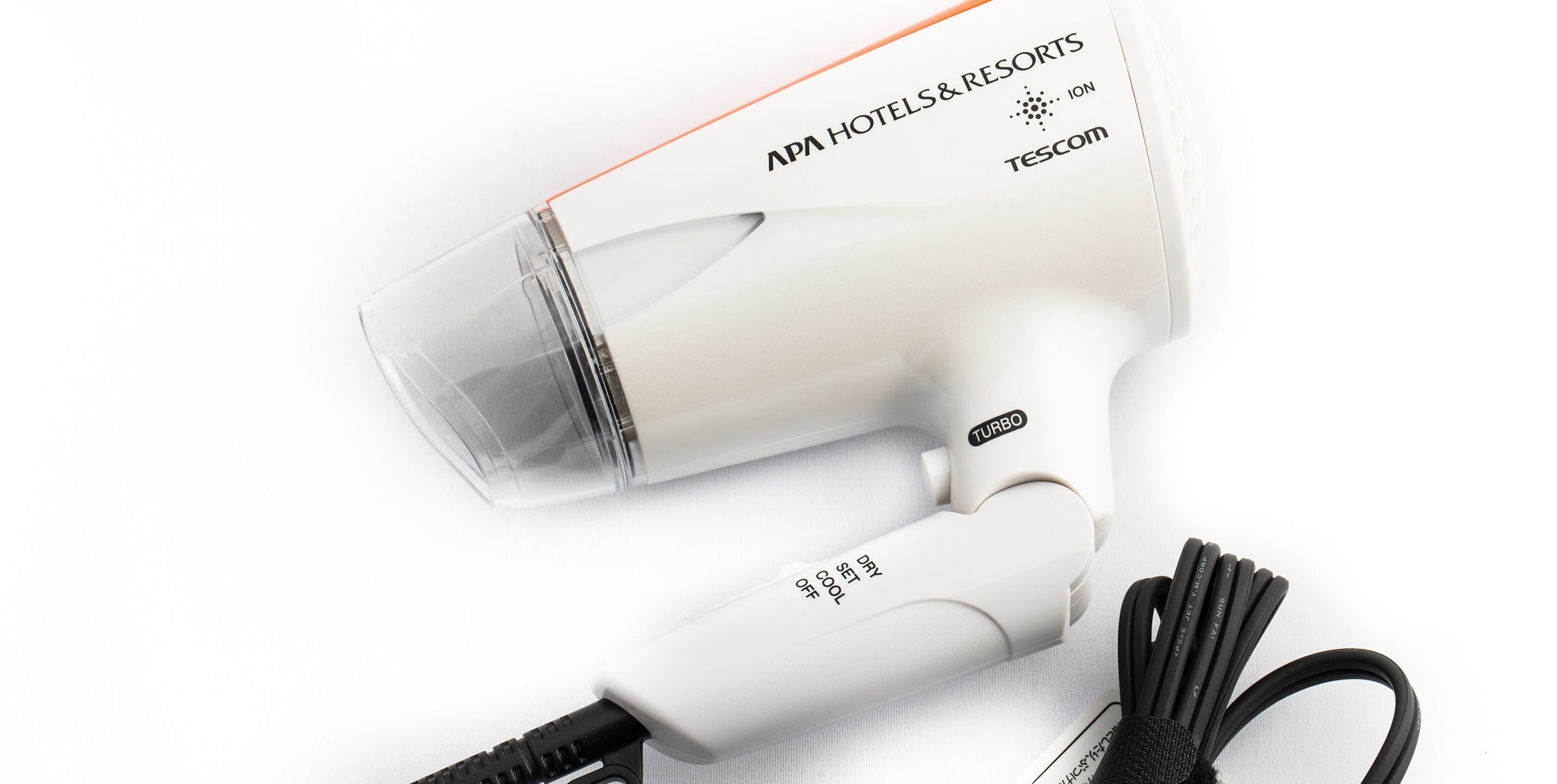 A white hair dryer with a transparent water bottle attached, a power cord, and a label reading "APA HOTELS & RESORTS" and "TESCOM".