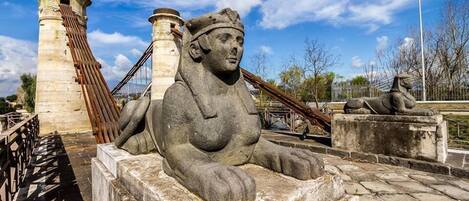 A stone statue of a reclining figure with a headpiece, set against a clear sky.