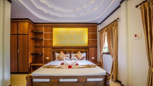 A spacious bedroom with a large bed, wooden headboard, and a decorative wall panel. - Phi Phi Andaman Beach Resort (Ko Phi Phi)