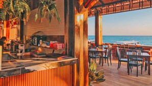 A restaurant with a view of the ocean, wooden deck, and hanging plants. - Phi Phi Andaman Beach Resort (Ko Phi Phi)