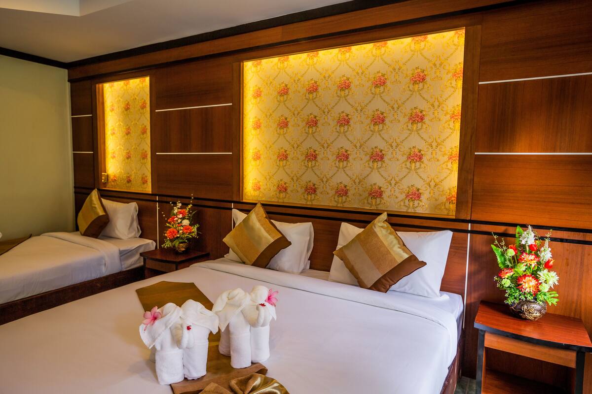 Une chambre d’hôtel avec un grand lit, deux tables de chevet, une petite table et un miroir fixé au mur.