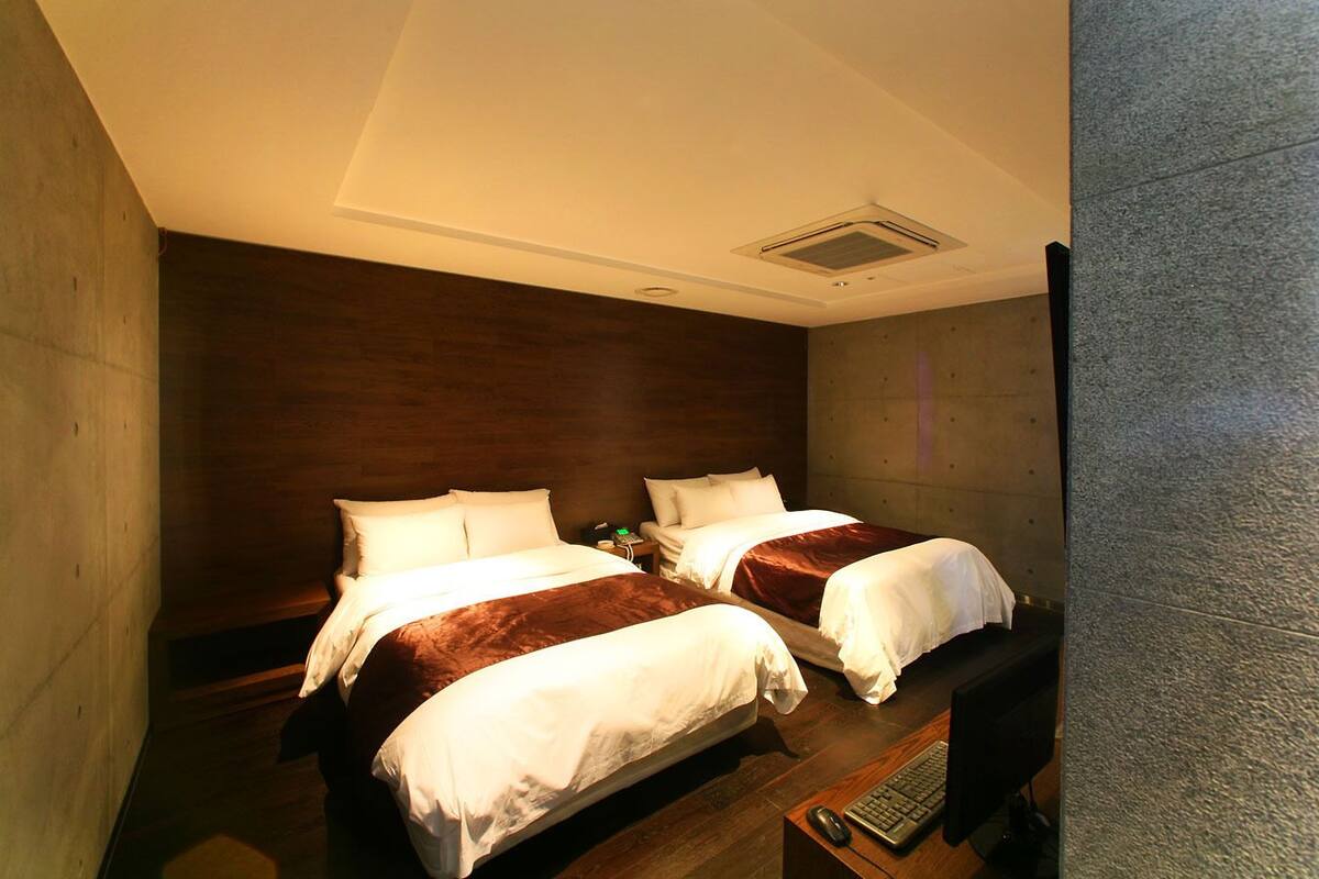 A hotel room with two beds, a desk with a computer, and a small table.