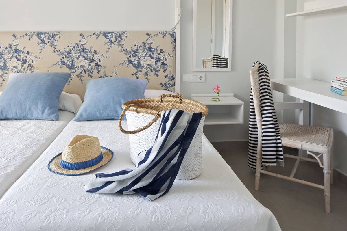 A neatly arranged bedroom with a bed, a chair, a desk, and a small table.