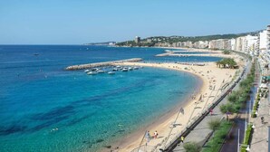A coastal cityscape with a beach, boats, and a promenade. - Hotel Rosamar (Calonge)