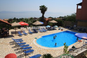 Una piscina al aire libre de temporada, sombrillas