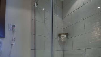 A modern bathroom with a glass-enclosed shower, a toilet, and a wall-mounted hand dryer.