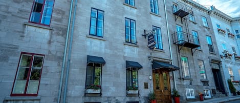 A historic building with a prominent entrance, multiple windows, and a fire escape.