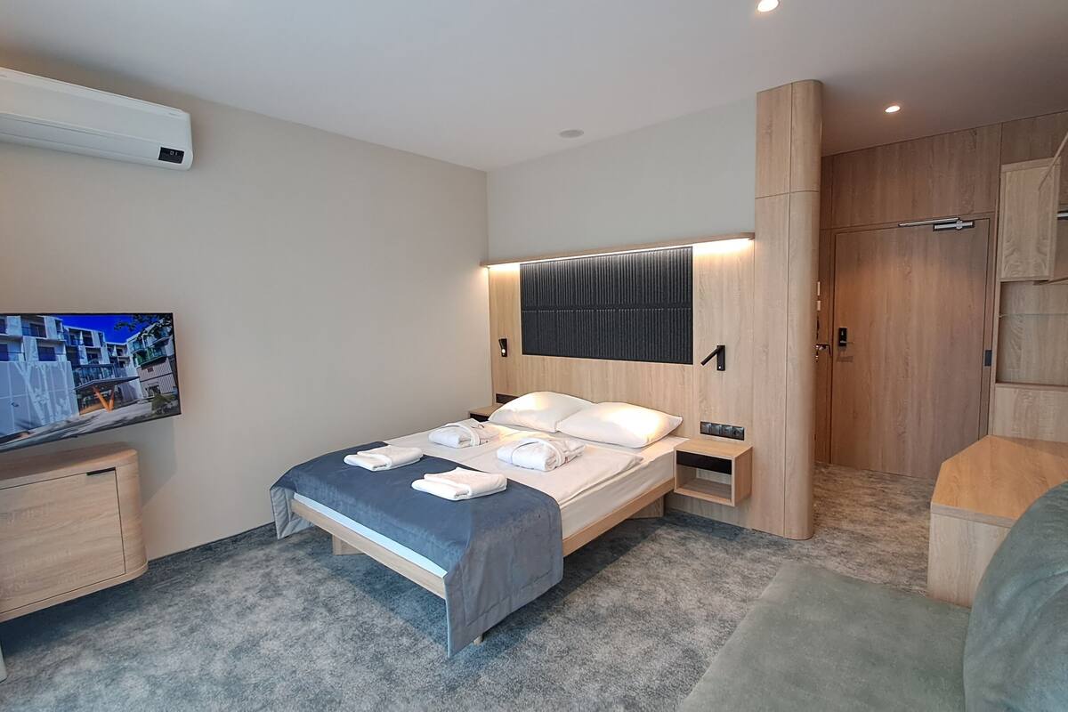 Una habitación de hotel moderna con cama, televisor, armario y baño.