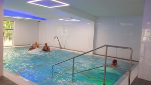 An indoor swimming pool with clear water, metal railings, and a tiled wall. - Verano (Kolobrzeg)