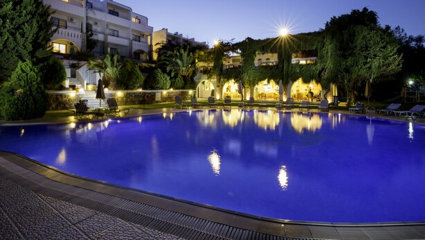 Una piscina con sillas de descanso y un edificio al fondo.