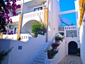 Ein weißes Gebäude mit einer Steinstufenanlage, Blumentöpfen und einem strahlend blauen Himmel.