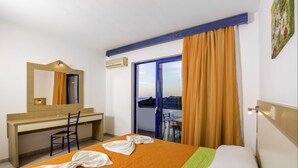 Habitación de hotel con cama, escritorio, silla, ventana con cortinas y vistas al exterior.