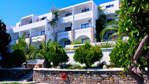 Un hotel de varios pisos con balcones, paredes de piedra y abundante vegetación.
