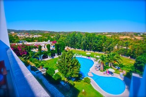Ein Resort mit Schwimmbad, umgeben von Palmen und Blick auf die Landschaft.