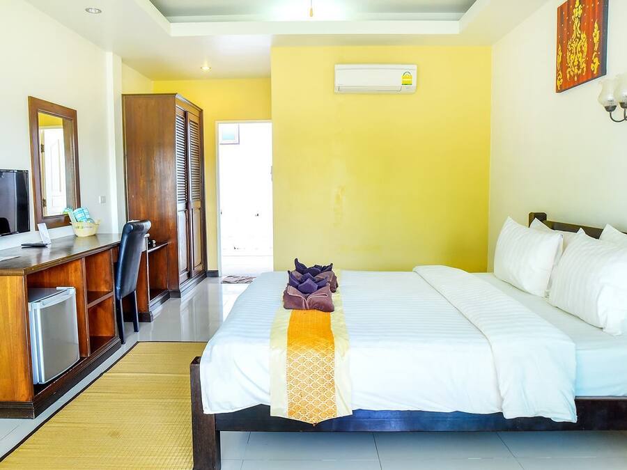 Een hotelkamer met een bed, een bureau met een computer, een kledingkast en een airconditioning.