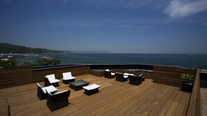 A wooden deck with outdoor seating and a view of the ocean.
