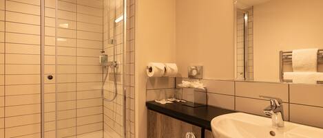 Un baño moderno con cabina de ducha de vidrio, un lavabo con espejo y un perchero para toallas.