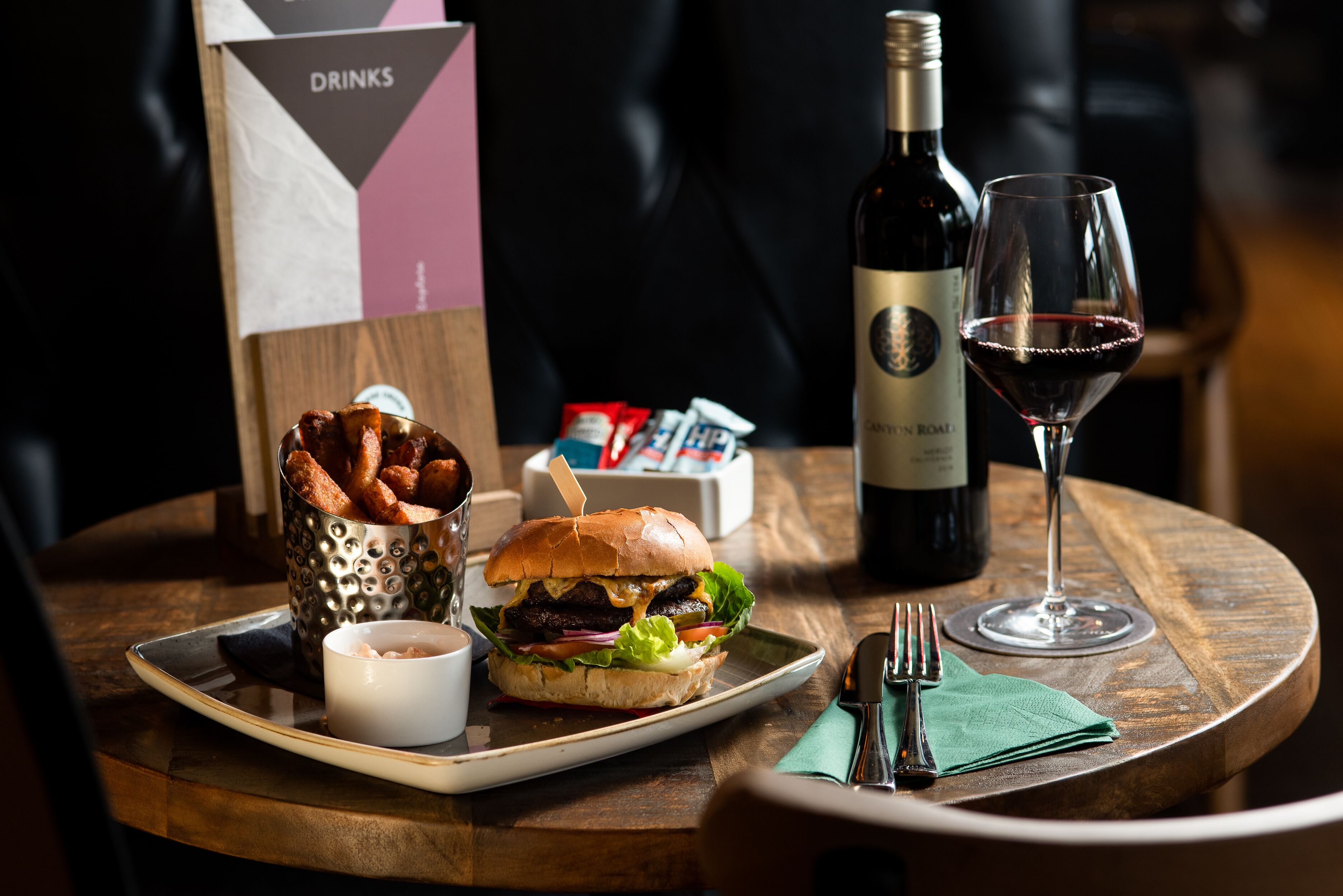 A meal tray with a burger, fries, and a drink on a wooden table.