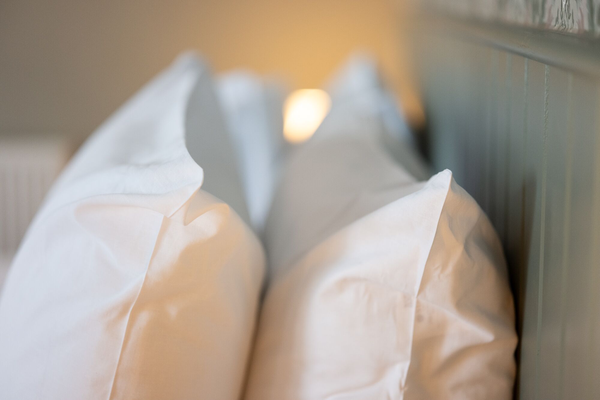 Primer plano de almohadas blancas contra una pared.
