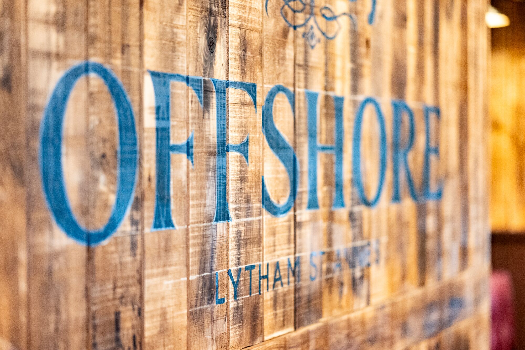 A wooden sign with the text "OFFSHORE" and "LITTLE SHORE" on it.