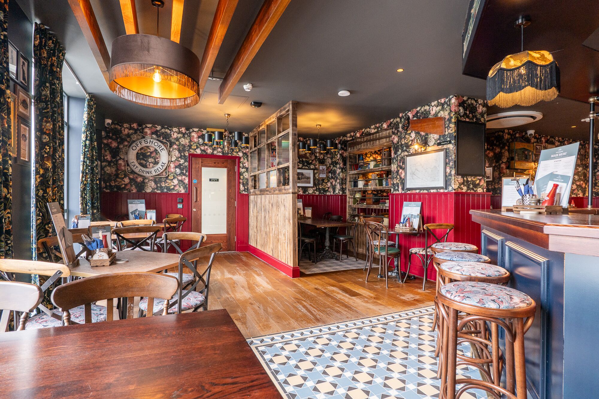 Un ristorante accogliente con arredi in legno, un'area bar e un pavimento decorato.