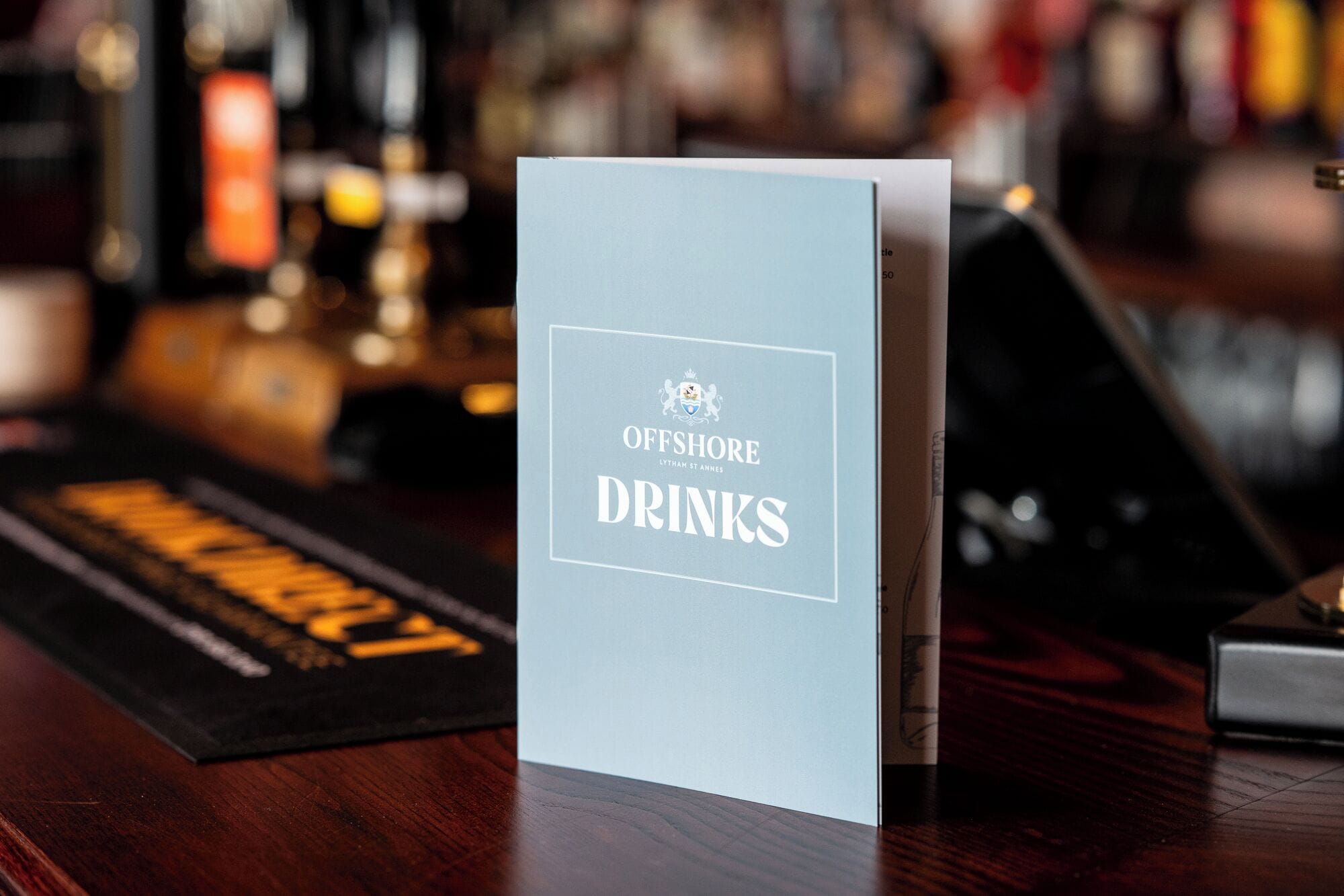 Quadro de menu do 'Offshore Drinks' em um bar.