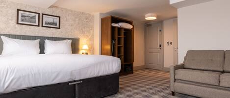A hotel room with a bed, a wardrobe, a chair, and a check-in desk.