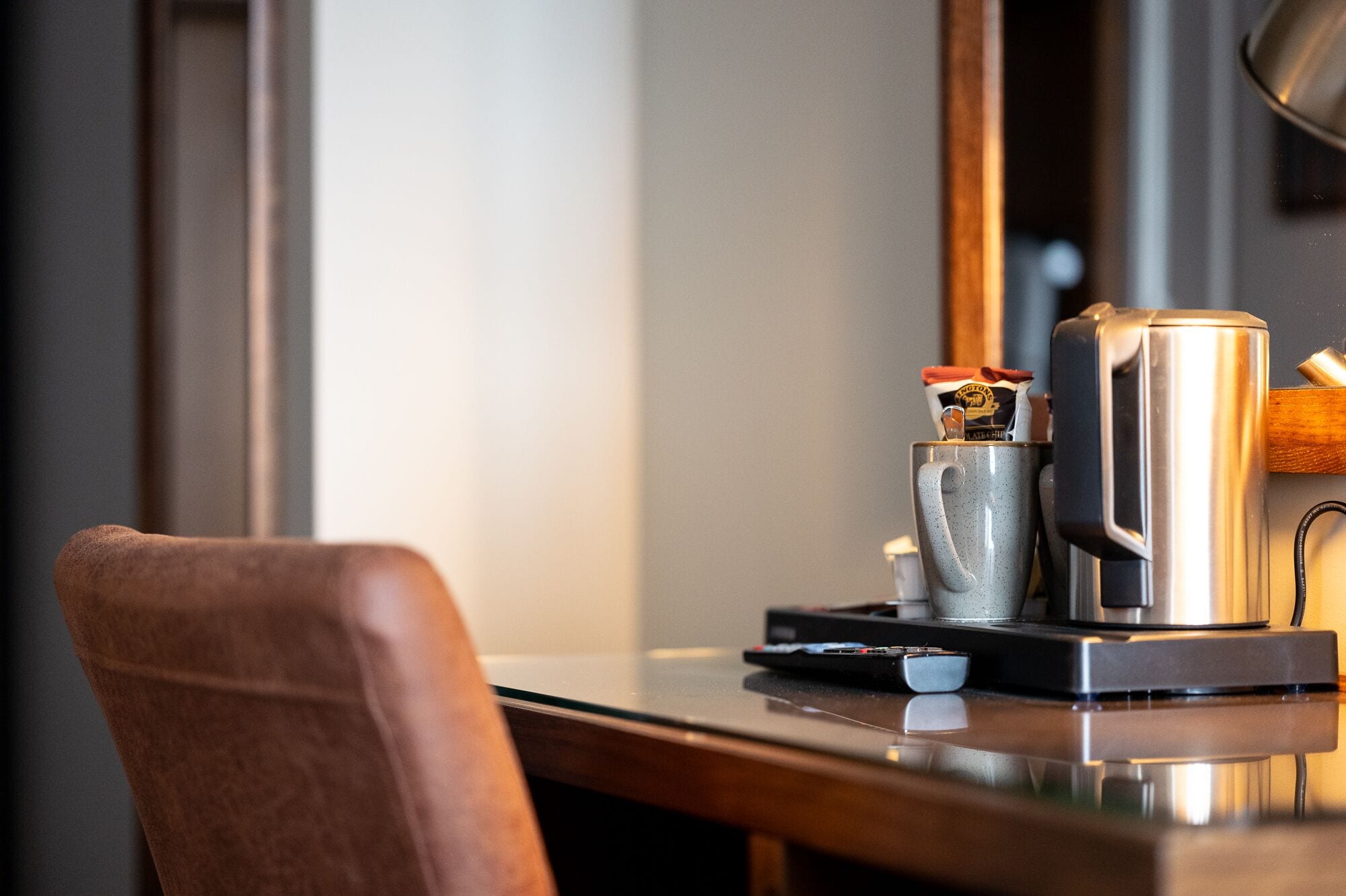 A kitchen counter with a coffee maker, a kettle, and a cup.