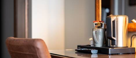 A kitchen counter with a coffee maker, a kettle, and a cup.