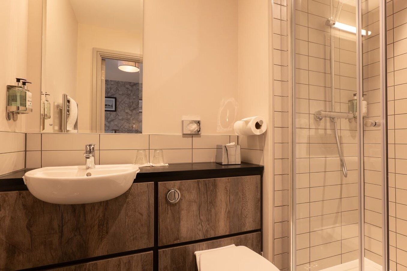 A modern bathroom with a large mirror, a sink, and a shower.