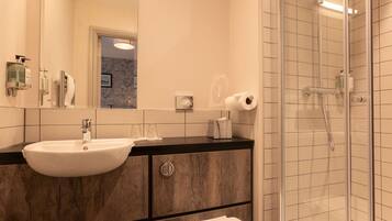 A modern bathroom with a large mirror, a sink, and a shower.