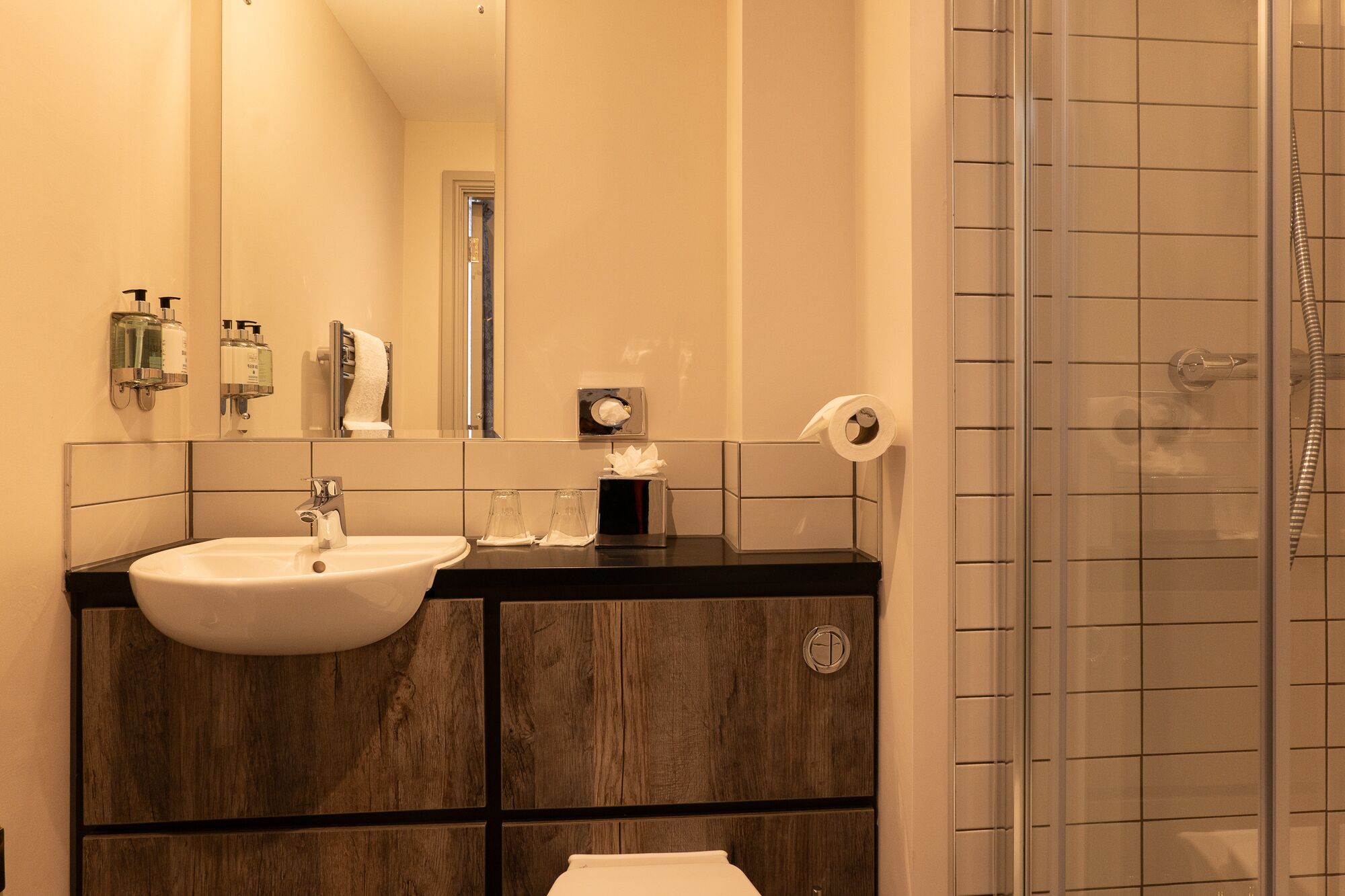 A bathroom with a white sink, mirror, and a shower area.