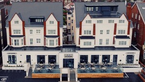 A hotel with a modern design, featuring a central entrance, outdoor seating area, and a view of the surrounding neighborhood. - Offshore - The Inn Collection Group (Lytham St. Anne's)