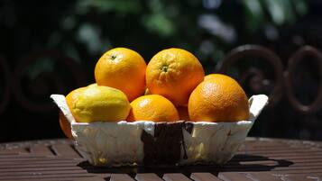 A basket of oranges and a lemon on a metal table.