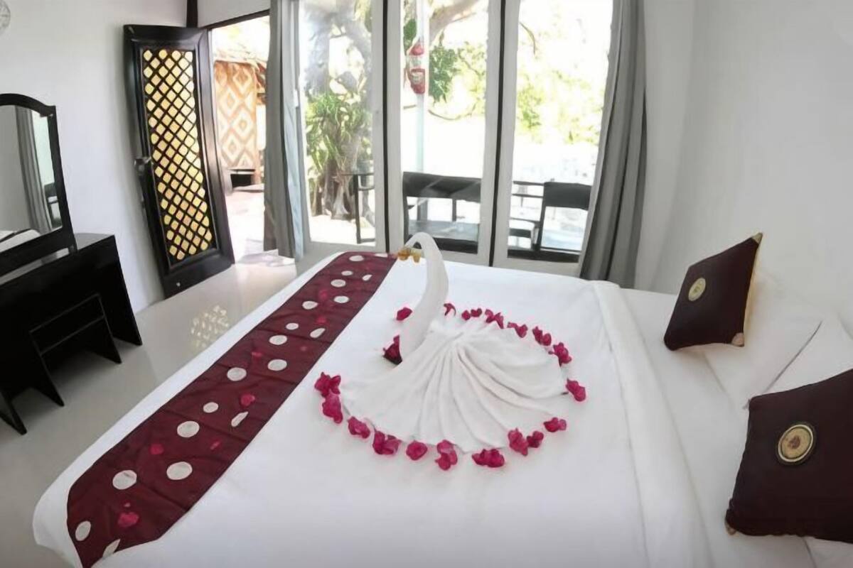 Habitación de hotel con cama, cómoda, espejo y vista al exterior.