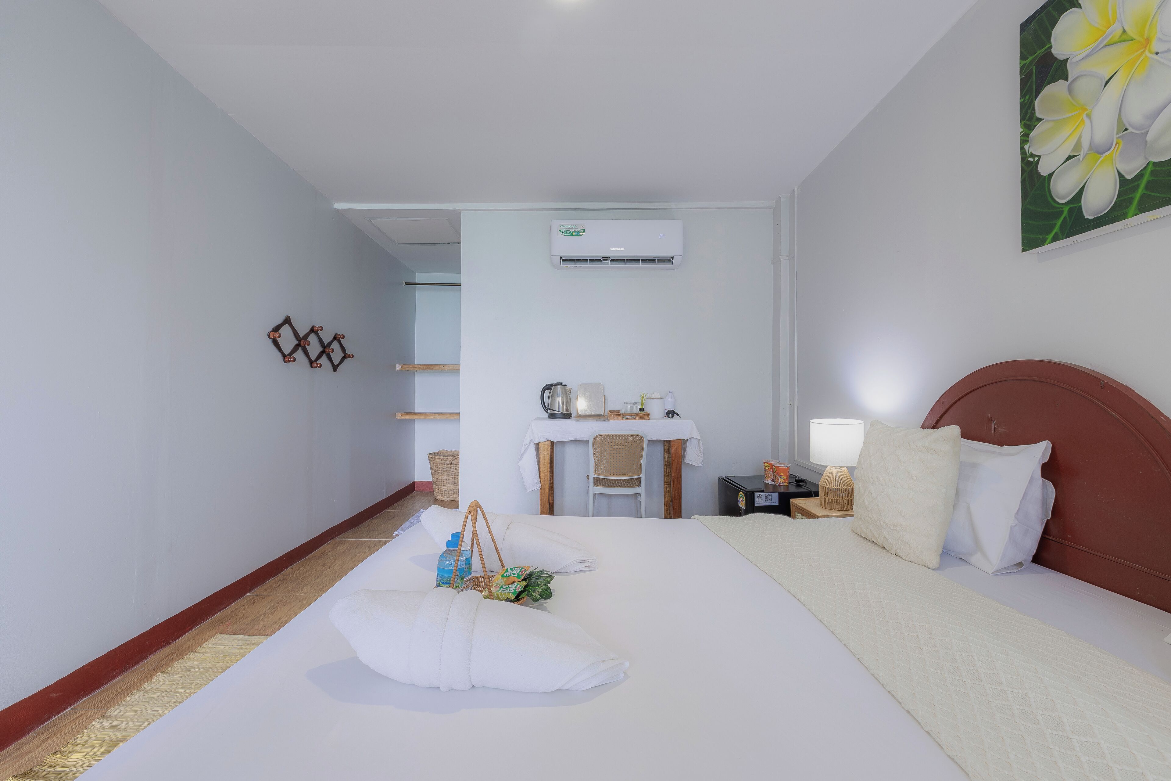 Una habitación de hotel con una cama grande, un escritorio con silla, una mesita pequeña y un aire acondicionado de pared.