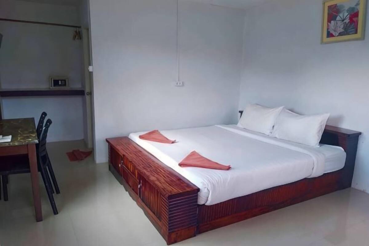 Un dormitorio con cama de madera, ropa de cama blanca, un escritorio y una silla.