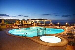 Una piscina al aire libre, sillones reclinables de piscina