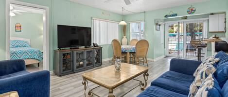 A living room with a TV, sofa, coffee table, and dining area.