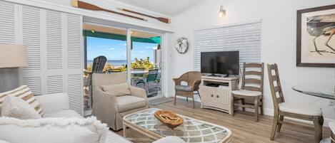 Ein großzügiger Wohnbereich mit Sofa, Sesseln, einem Glastisch und einem Fernseher.