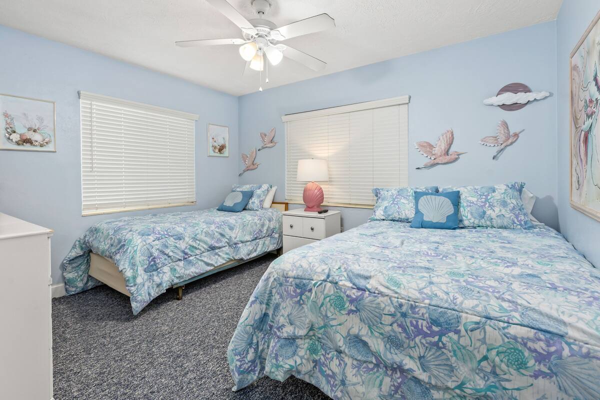 Ein Schlafzimmer mit zwei Betten, einem Deckenventilator und Bildern an den Wänden.