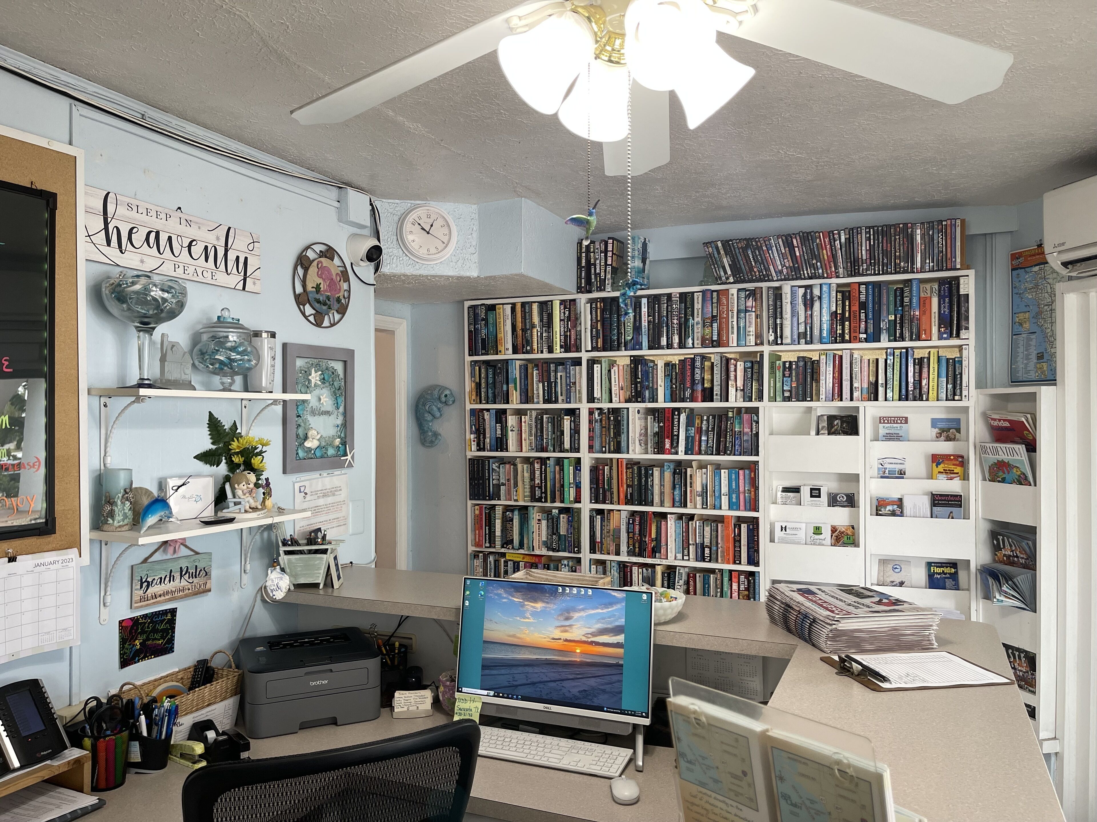 Un bureau à domicile équipé d’une grande bibliothèque, d’un bureau, d’un ordinateur et de divers objets décoratifs.