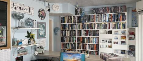 Un bureau à domicile équipé d’une grande bibliothèque, d’un bureau, d’un ordinateur et de divers objets décoratifs.