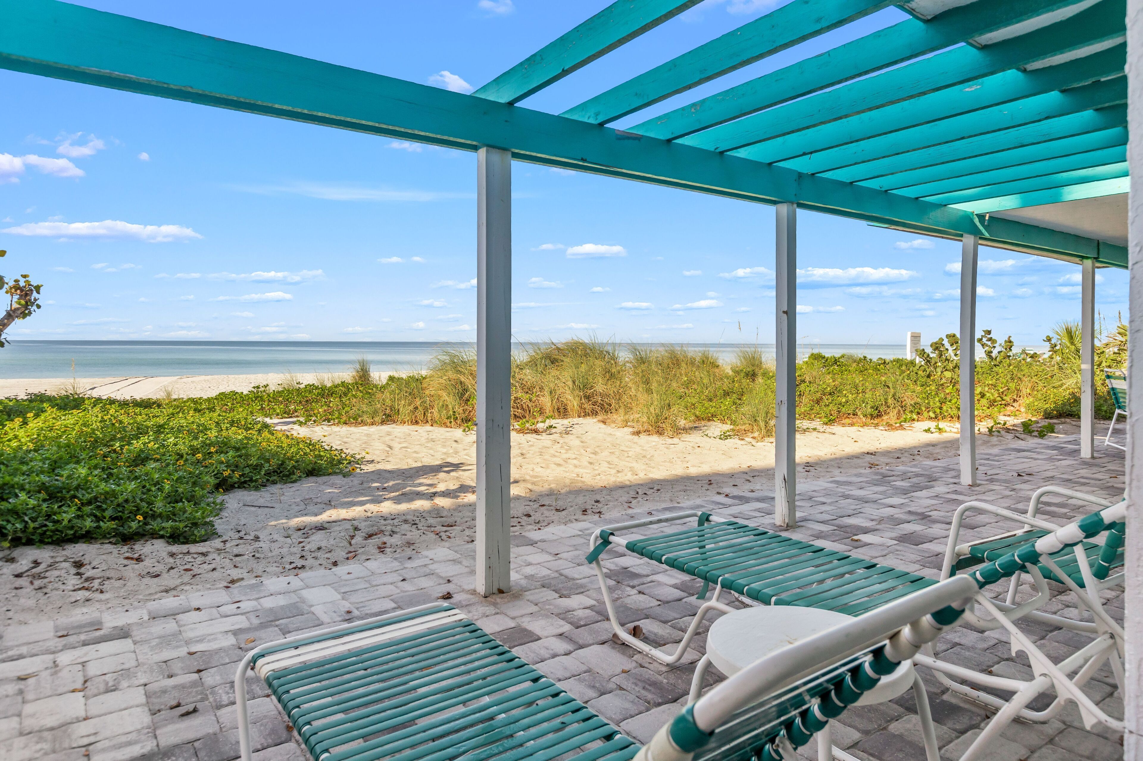A covered outdoor seating area with a view of the beach and ocean.